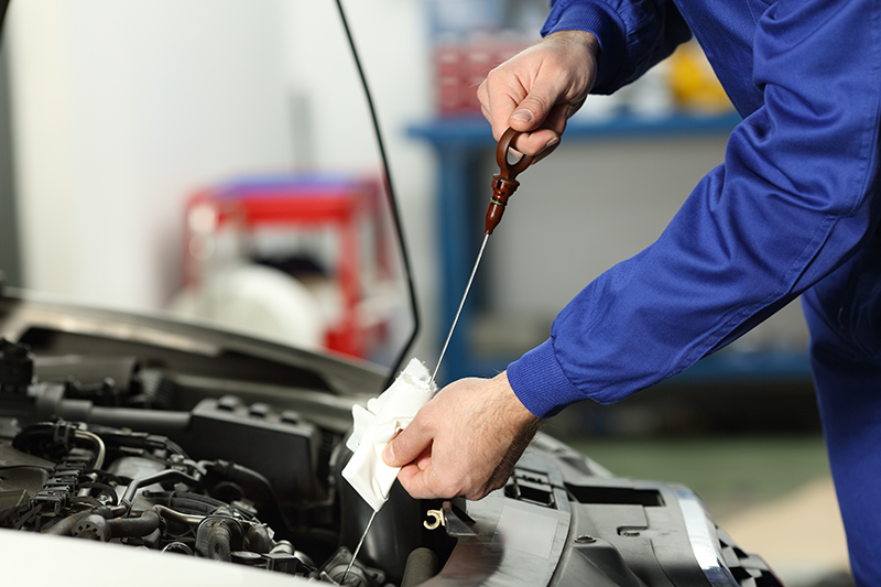A mechanic checking a dipstick - Oil Changes: FAQs for Chevy Owners