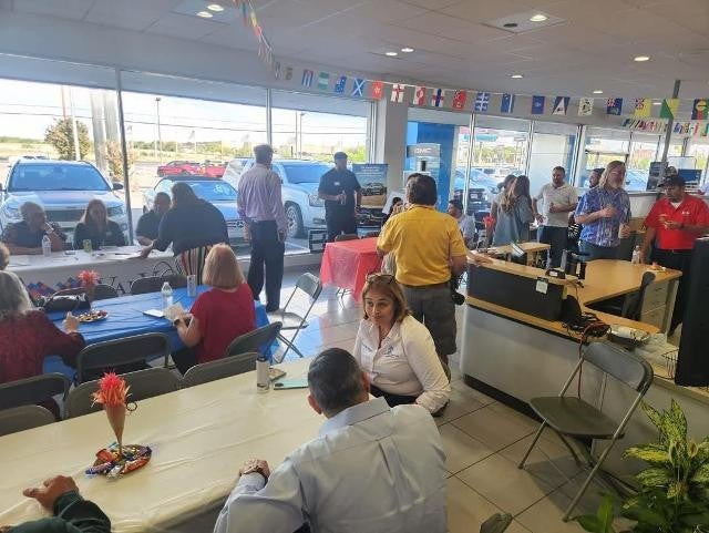 People dining and mingling under world flags during festive dealership event