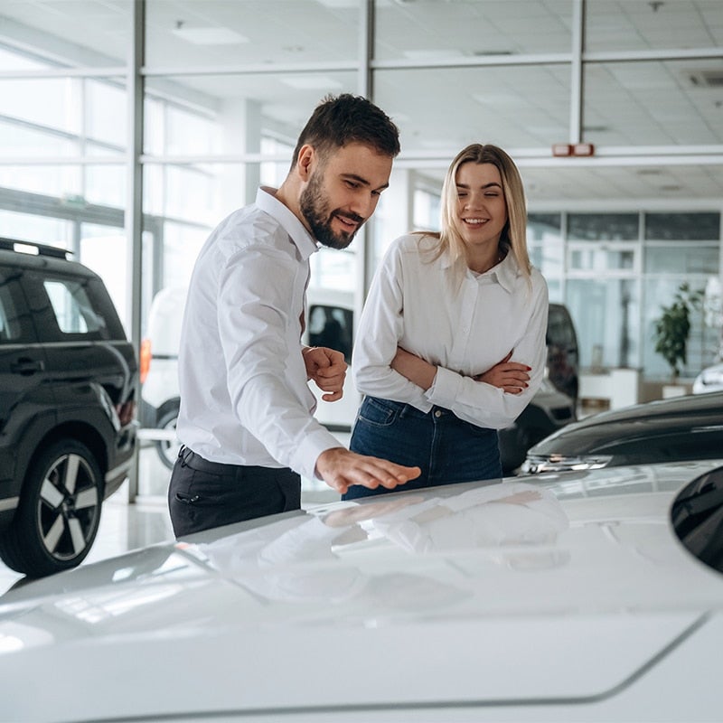 Customer and salesperson inspecting car in showroom